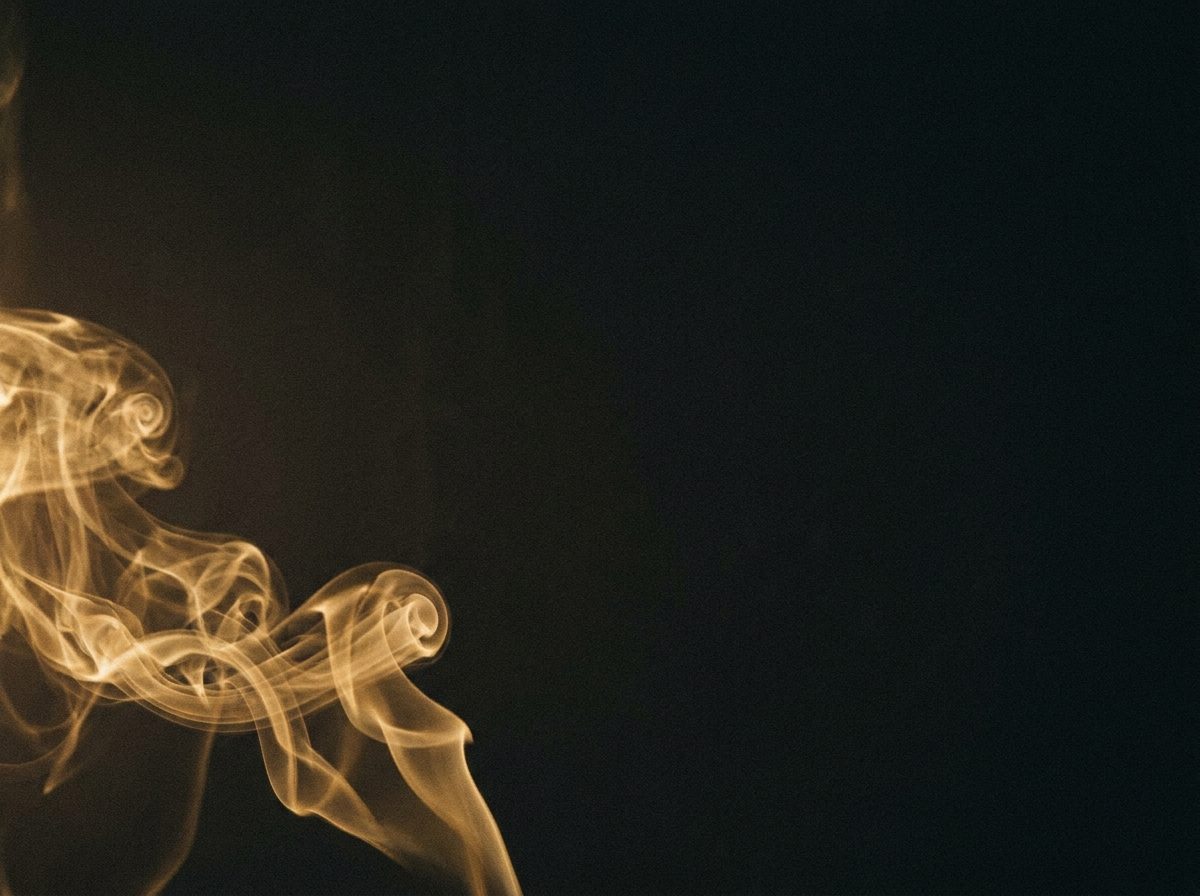 Ribbons of steam curling through darkness, lit from the side.